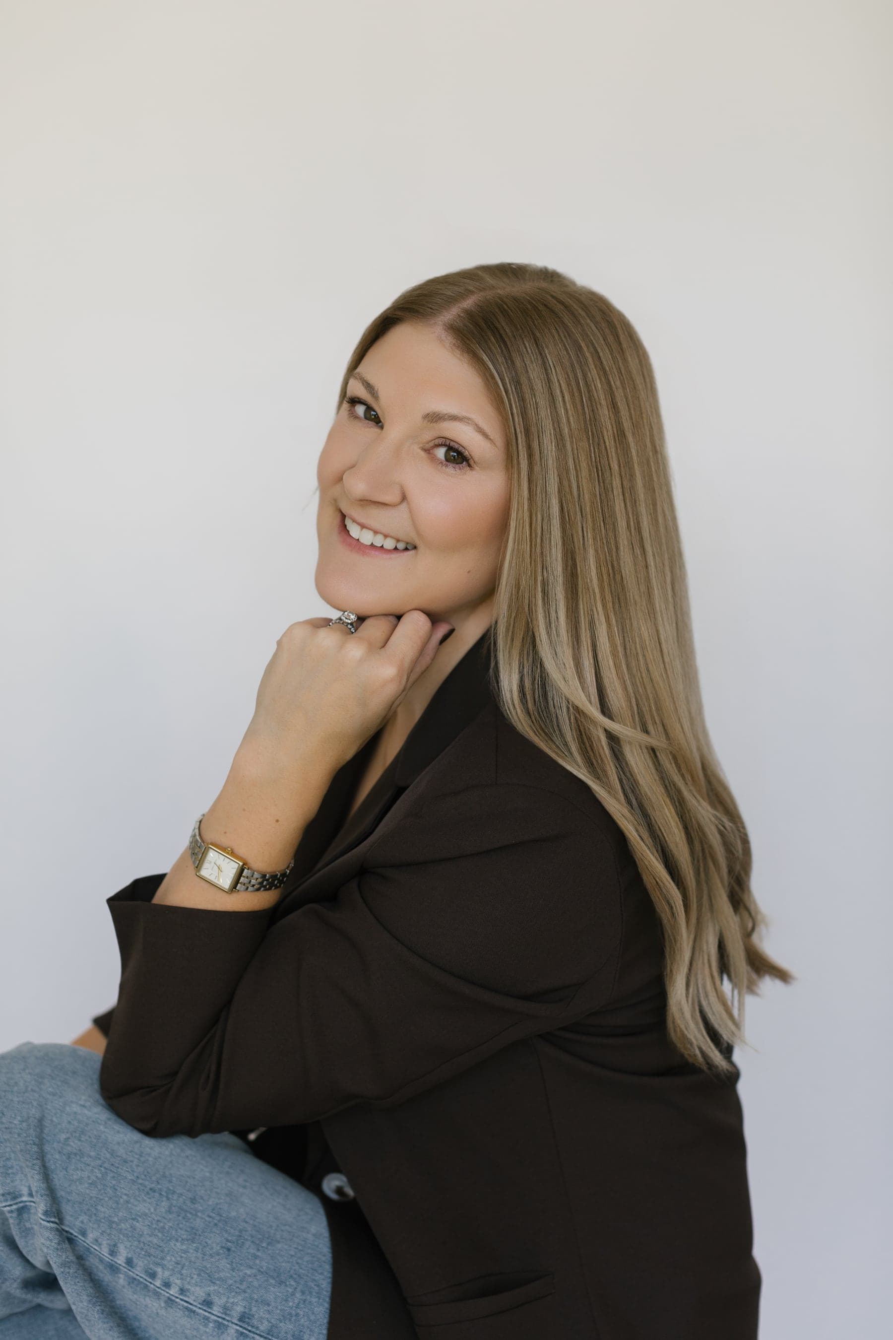 Brittany Saari, owner and principal planner of Walker & West, smiling over her shoulder in a dark brown blazer and jeans