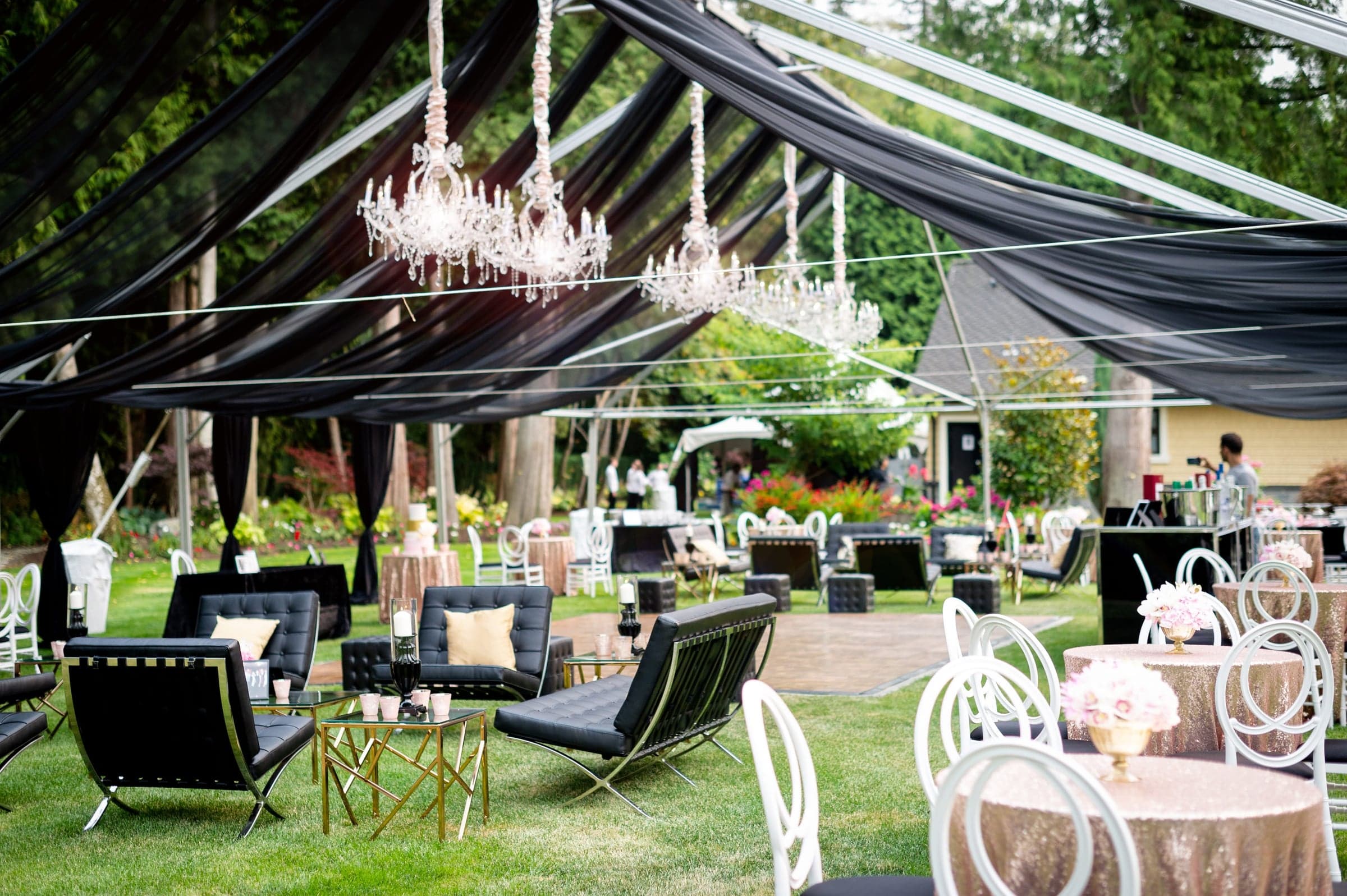 A garden tent draped in black chiffon with crystal chandeliers, leather lounge seating and blush sequin cocktail tables
